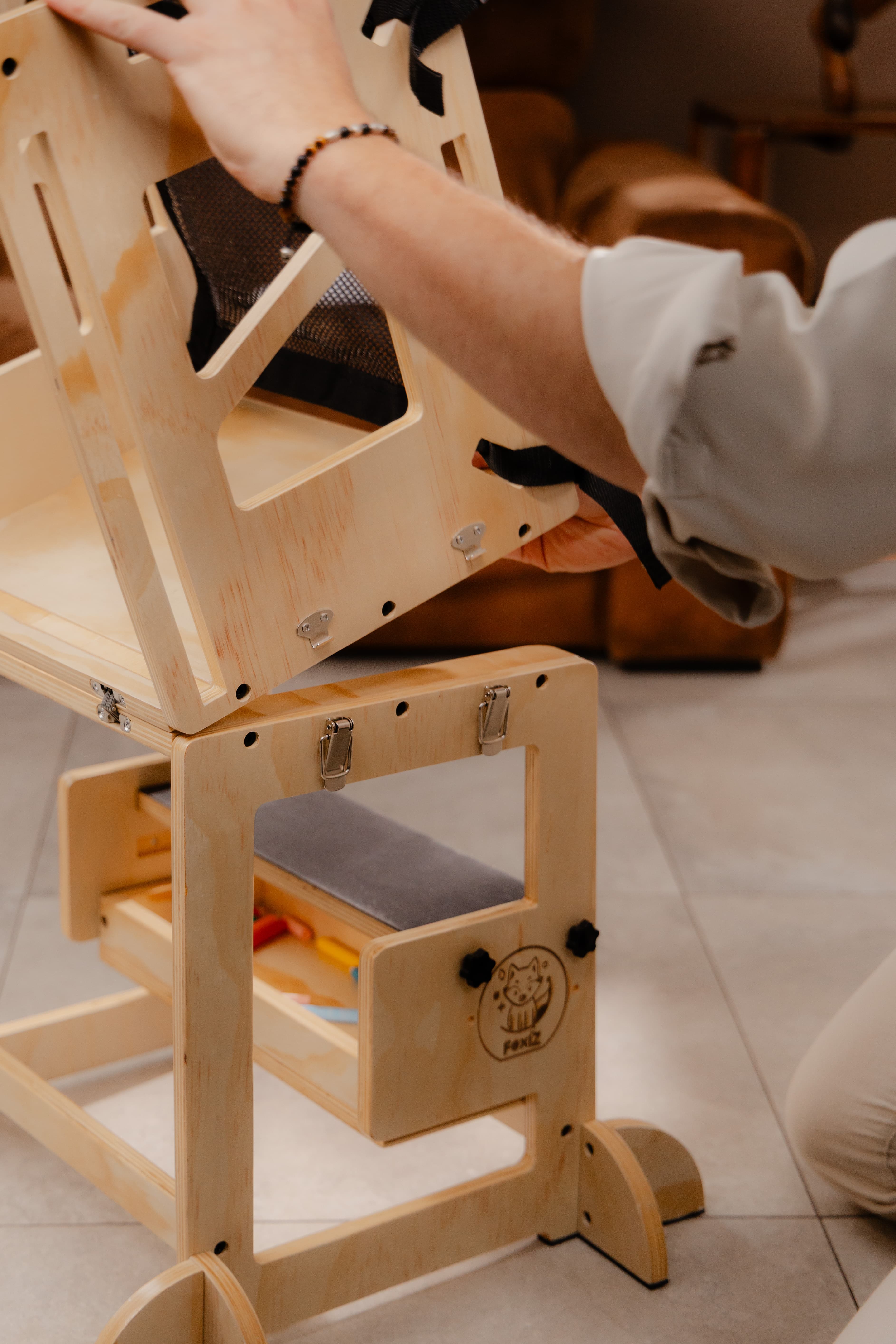 Adulte transformant la VersaTower, tour d'apprentissage Montessori évolutive, en mode table et banc