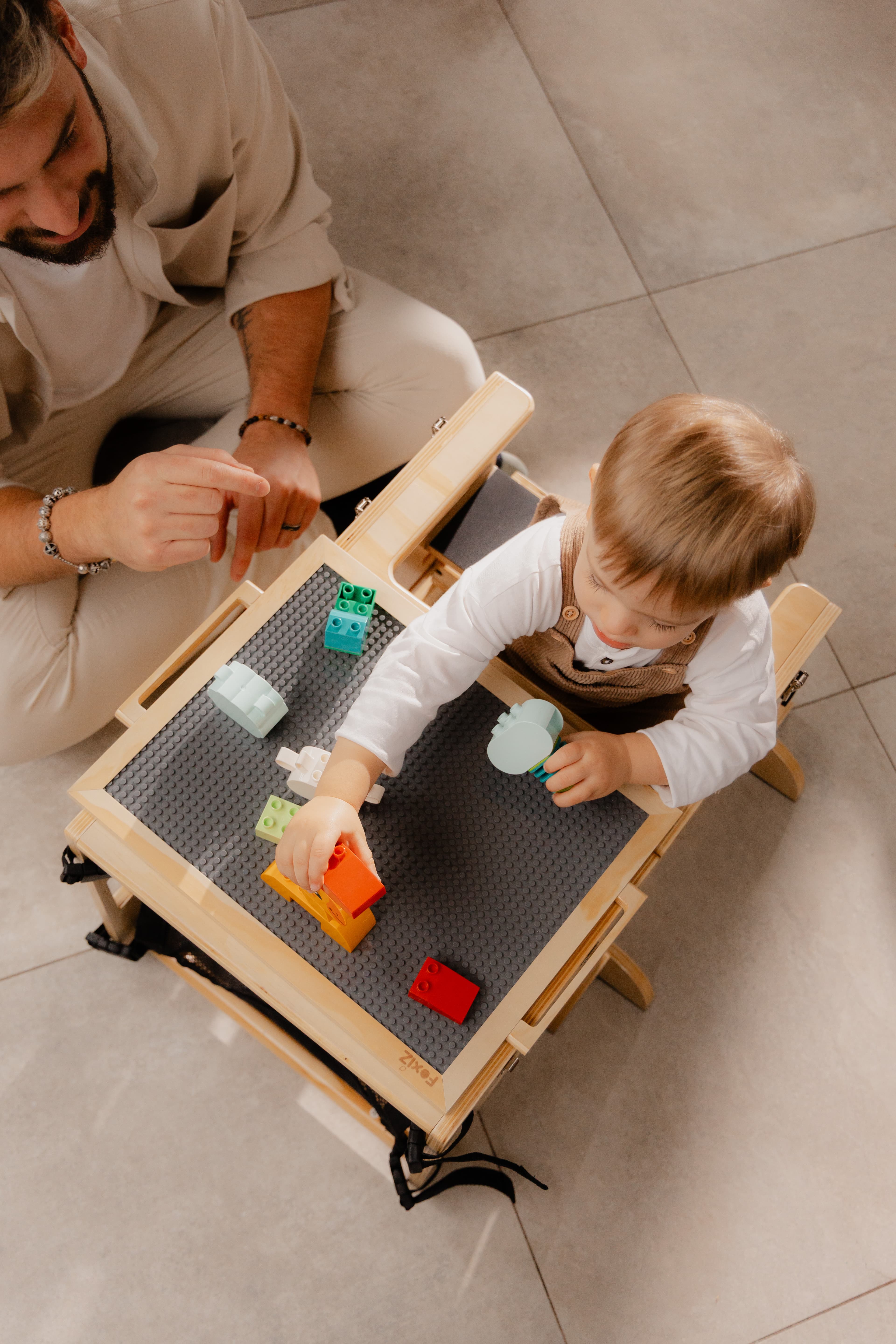 Papa et enfant jouant aux briques sur le plateau de la VersaTower Montessori, vus de dessus