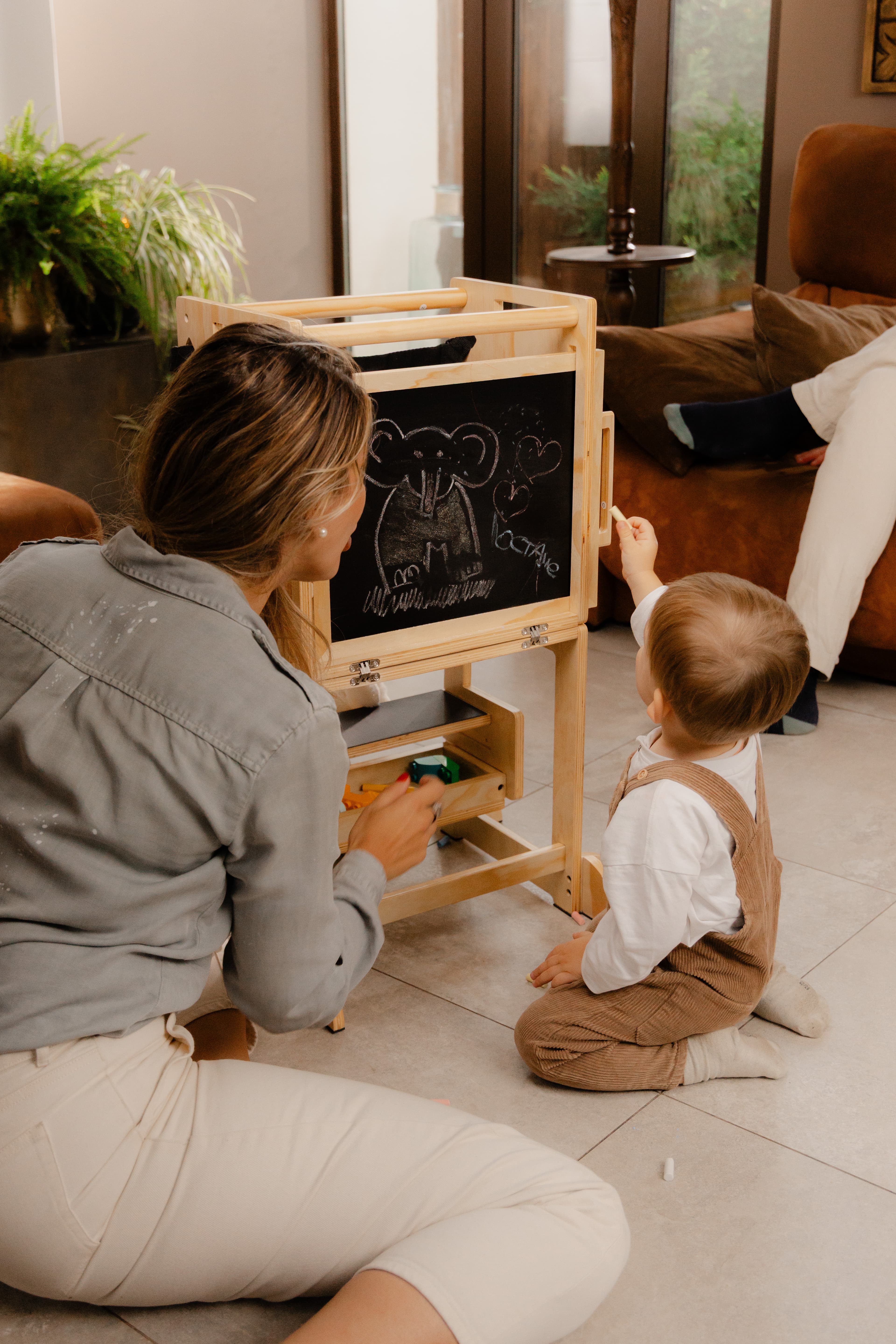 Maman et enfant dessinant au tableau noir de la VersaTower, tour Montessori évolutive