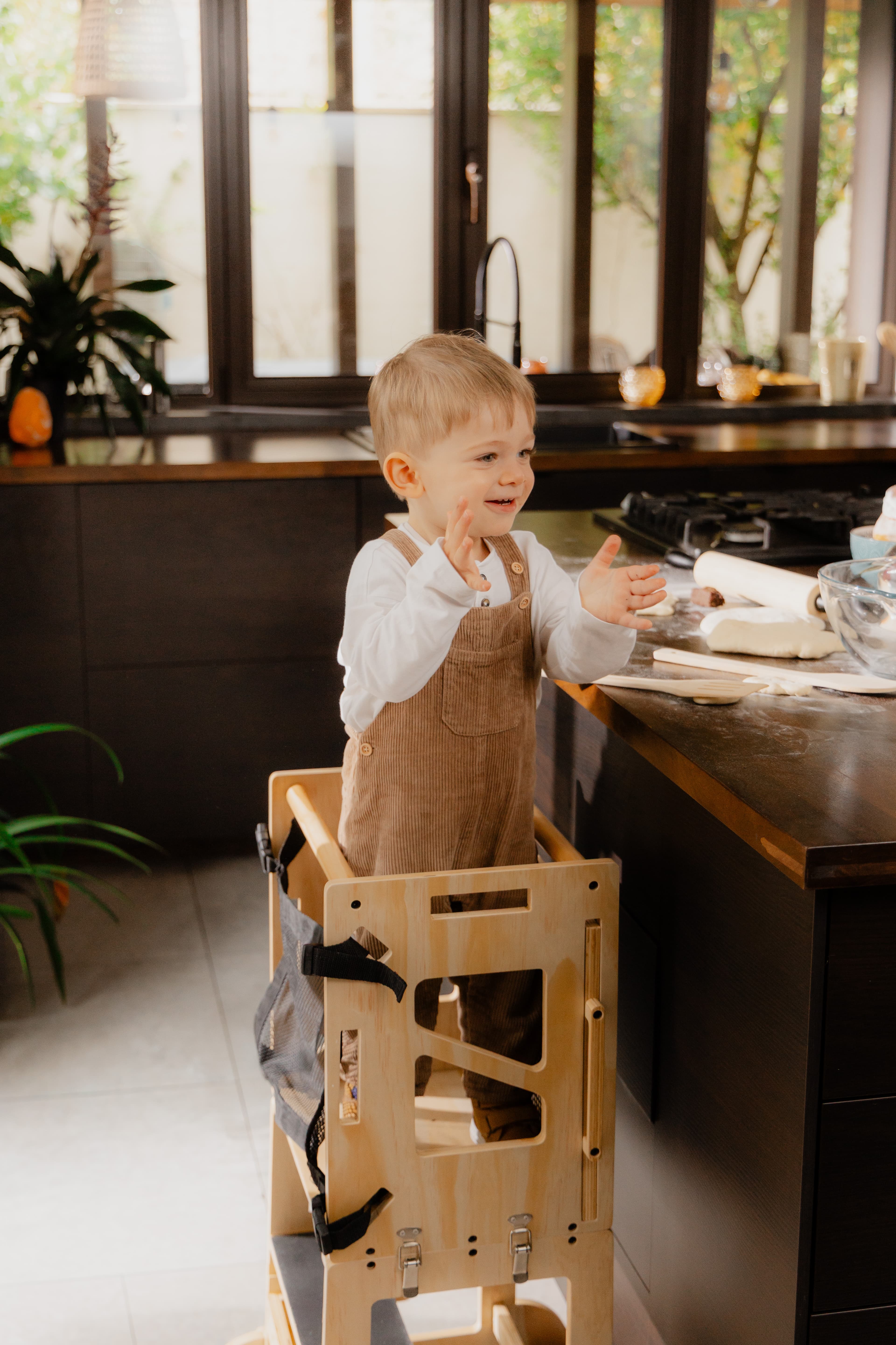 Enfant souriant dans la VersaTower devant le plan de travail de la cuisine