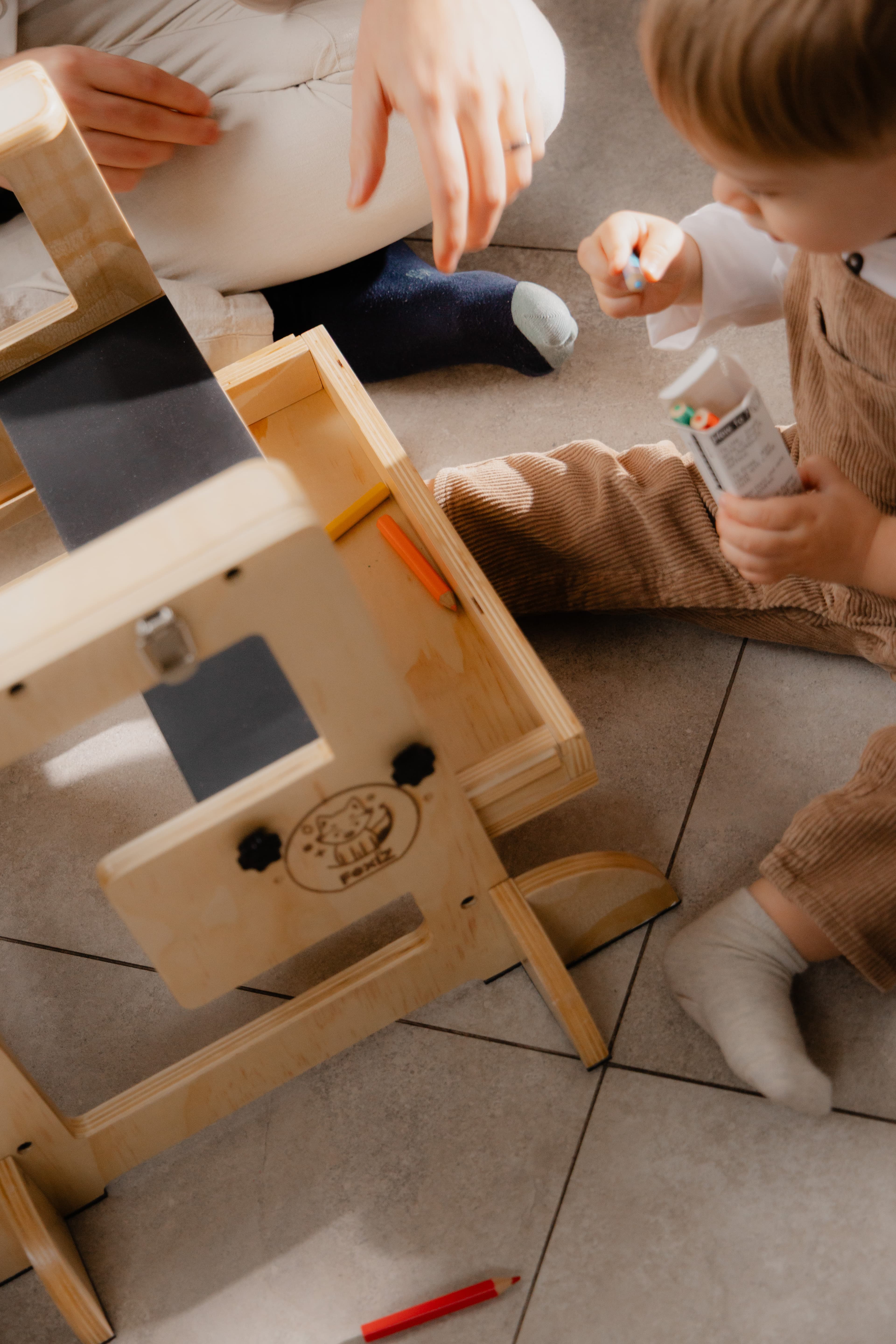 Parent et enfant assemblant ensemble la VersaTower, tour d'apprentissage Montessori